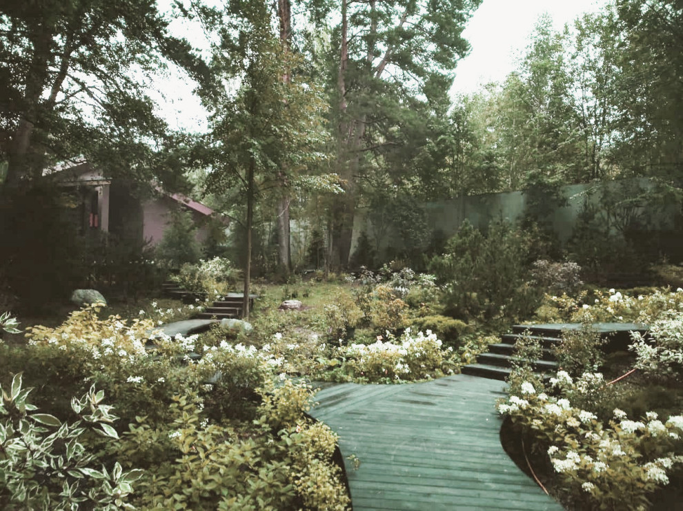На фото: большой летний участок и сад на склоне с садовой дорожкой или калиткой, полуденной тенью, настилом и с каменным забором с