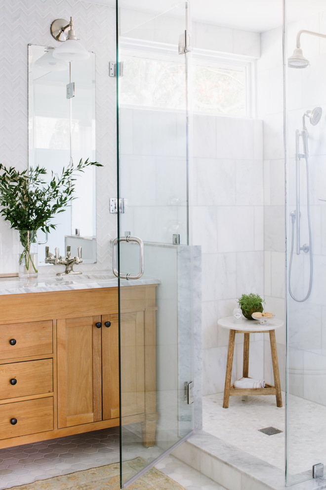 Inspiration for a mid-sized eclectic master bathroom in Austin with furniture-like cabinets, light wood cabinets, a corner shower, a two-piece toilet, white tile, glass sheet wall, blue walls, marble floors, an undermount sink, marble benchtops, grey floor and a shower curtain.