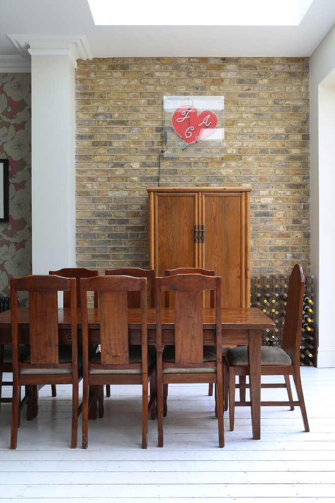 This is an example of a transitional dining room in London with brown walls and painted wood floors.
