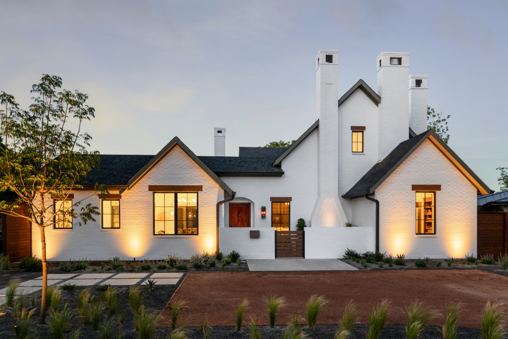 Aménagement d'une grande façade de maison blanche classique en brique de plain-pied avec un toit à deux pans, un toit en shingle et un toit noir.