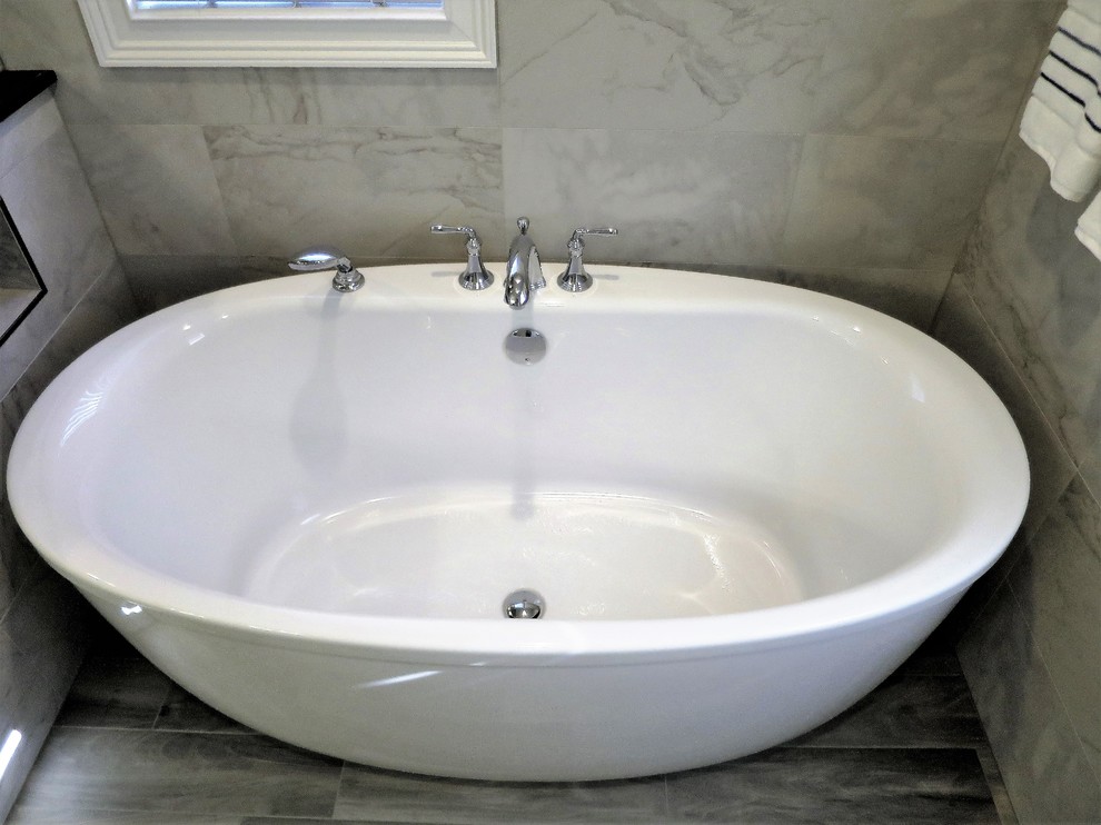 Mid-sized transitional master gray tile and porcelain tile porcelain tile and gray floor freestanding bathtub photo in Bridgeport with shaker cabinets, white cabinets, a one-piece toilet, blue walls, an integrated sink, solid surface countertops and a hinged shower door