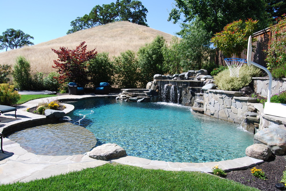 Photo of an expansive country backyard custom-shaped natural pool in San Francisco with a water feature and natural stone pavers.