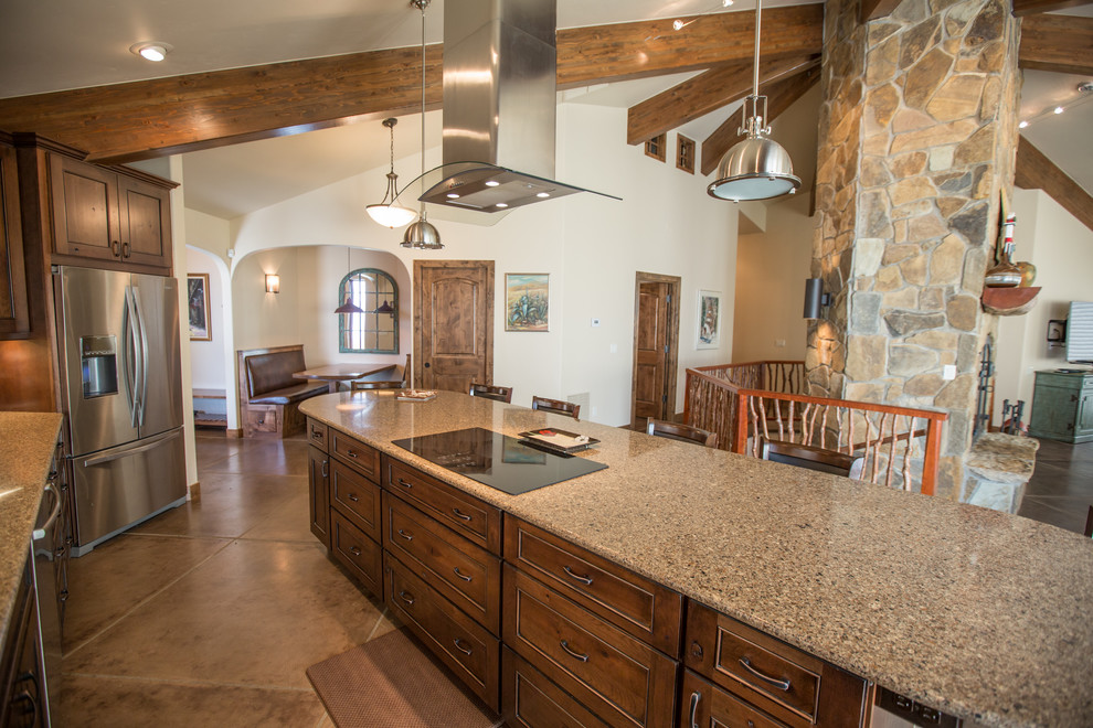 Inspiration for a mid-sized rustic single-wall concrete floor and gray floor open concept kitchen remodel in Denver with an undermount sink, recessed-panel cabinets, dark wood cabinets, granite countertops, beige backsplash, stone slab backsplash, stainless steel appliances and an island