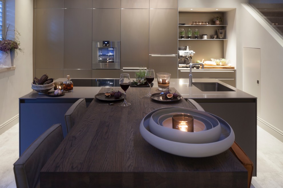 This is an example of a mid-sized contemporary single-wall kitchen in West Midlands with an undermount sink, flat-panel cabinets, solid surface benchtops, stainless steel appliances, porcelain floors and with island.