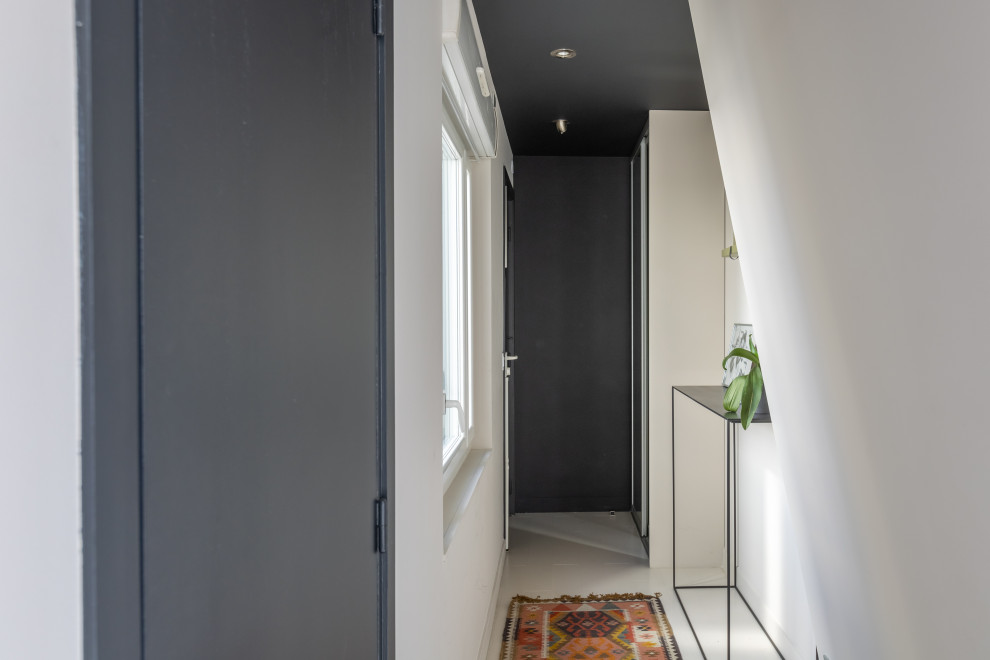 Modern inredning av en mellanstor farstu, med svarta väggar, målat trägolv, en enkeldörr, en svart dörr och vitt golv