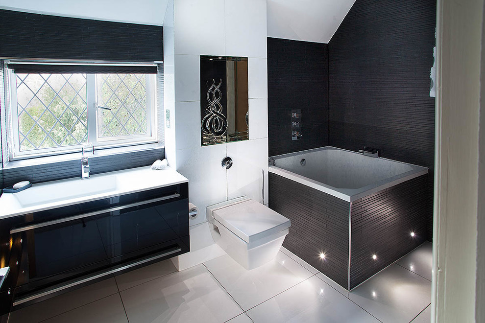 This is an example of a mid-sized modern bathroom in London with a wall-mount toilet, white tile, porcelain tile, brown walls, porcelain floors, flat-panel cabinets, dark wood cabinets, a shower/bathtub combo, a wall-mount sink, solid surface benchtops and a japanese tub.