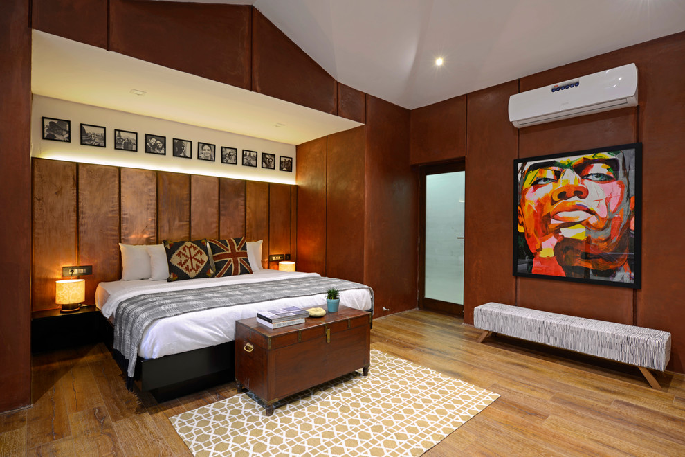 Inspiration for a tropical master bedroom in Mumbai with brown walls, light hardwood floors, no fireplace and beige floor.