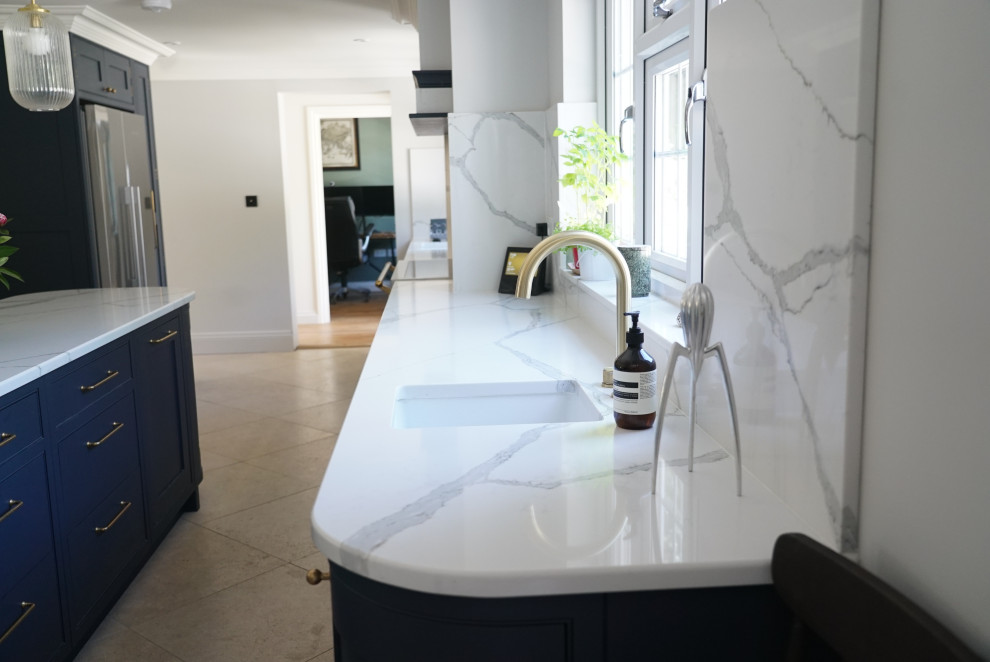 Example of a mid-sized trendy galley eat-in kitchen design in Surrey with a farmhouse sink, shaker cabinets, blue cabinets, quartzite countertops, white backsplash, quartz backsplash, colored appliances, an island and white countertops