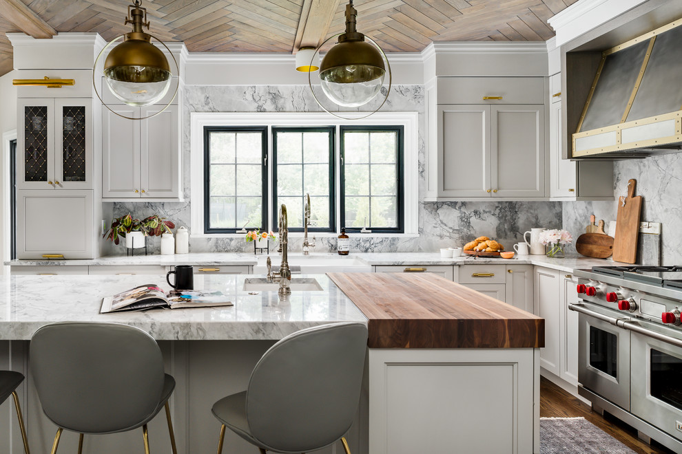 This is an example of a mid-sized transitional separate kitchen in Chicago with a farmhouse sink, recessed-panel cabinets, grey cabinets, quartzite benchtops, grey splashback, stone slab splashback, panelled appliances, medium hardwood floors, with island, brown floor and grey benchtop.