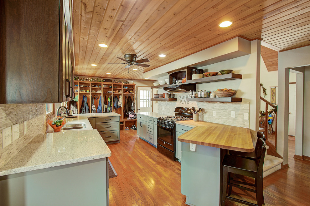 Mid-sized transitional galley medium tone wood floor and brown floor eat-in kitchen photo with an undermount sink, shaker cabinets, gray cabinets, quartz countertops, gray backsplash, stone tile backsplash, black appliances, a peninsula and white countertops