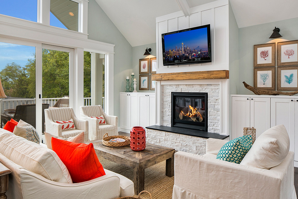 Design ideas for a beach style family room in Seattle with blue walls, a standard fireplace, a stone fireplace surround and a wall-mounted tv.