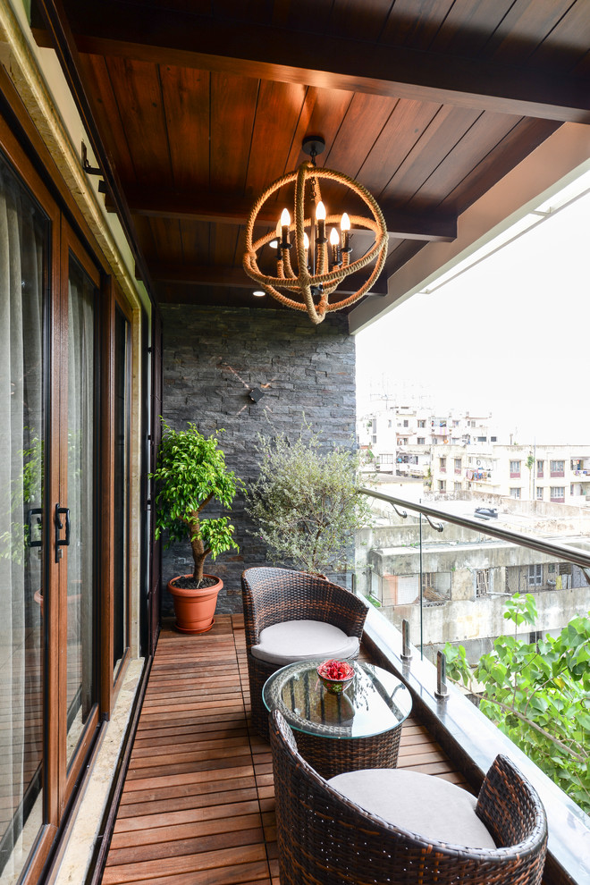 Contemporary balcony in Hyderabad with a roof extension and glass railing.
