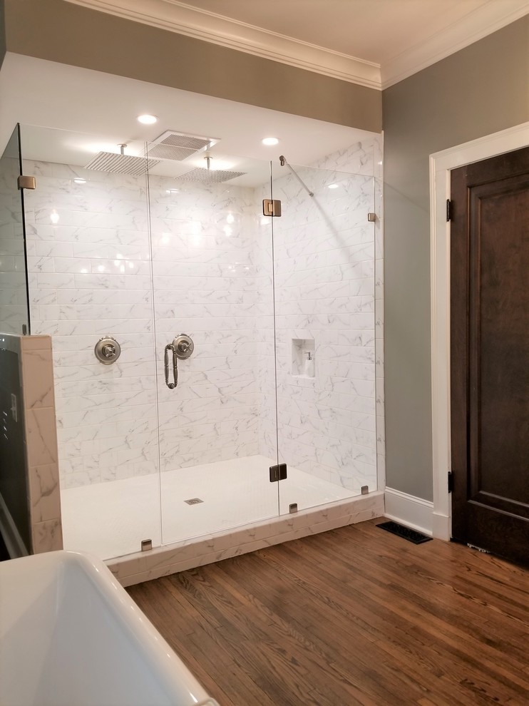 Inspiration for a mid-sized traditional master bathroom in Other with open cabinets, medium wood cabinets, a claw-foot tub, a double shower, a one-piece toilet, white tile, porcelain tile, grey walls, medium hardwood floors, a vessel sink, brown floor and a hinged shower door.