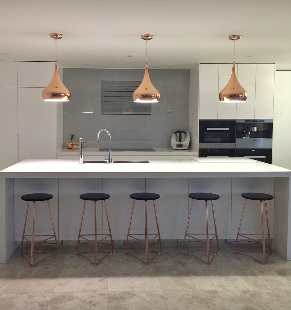 Inspiration for a large contemporary single-wall eat-in kitchen in Sydney with an undermount sink, flat-panel cabinets, white cabinets, quartz benchtops, grey splashback, glass sheet splashback, black appliances, porcelain floors and with island.
