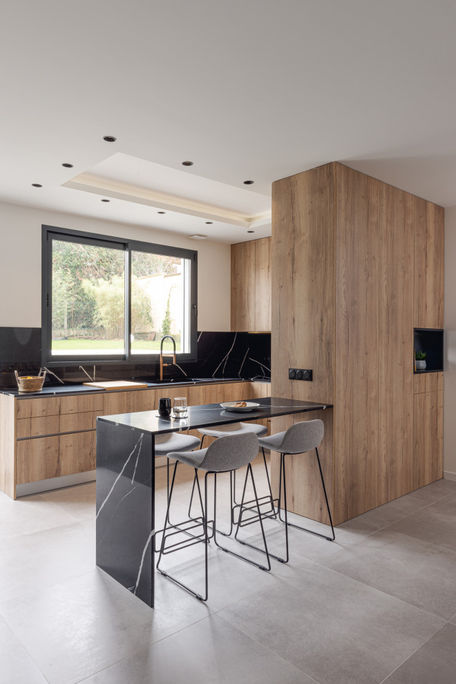 Inspiration for a large contemporary u-shaped open plan kitchen in Paris with a submerged sink, flat-panel cabinets, black cabinets, wood worktops, black splashback, marble splashback, black appliances, ceramic flooring, a breakfast bar, grey floors and beige worktops.