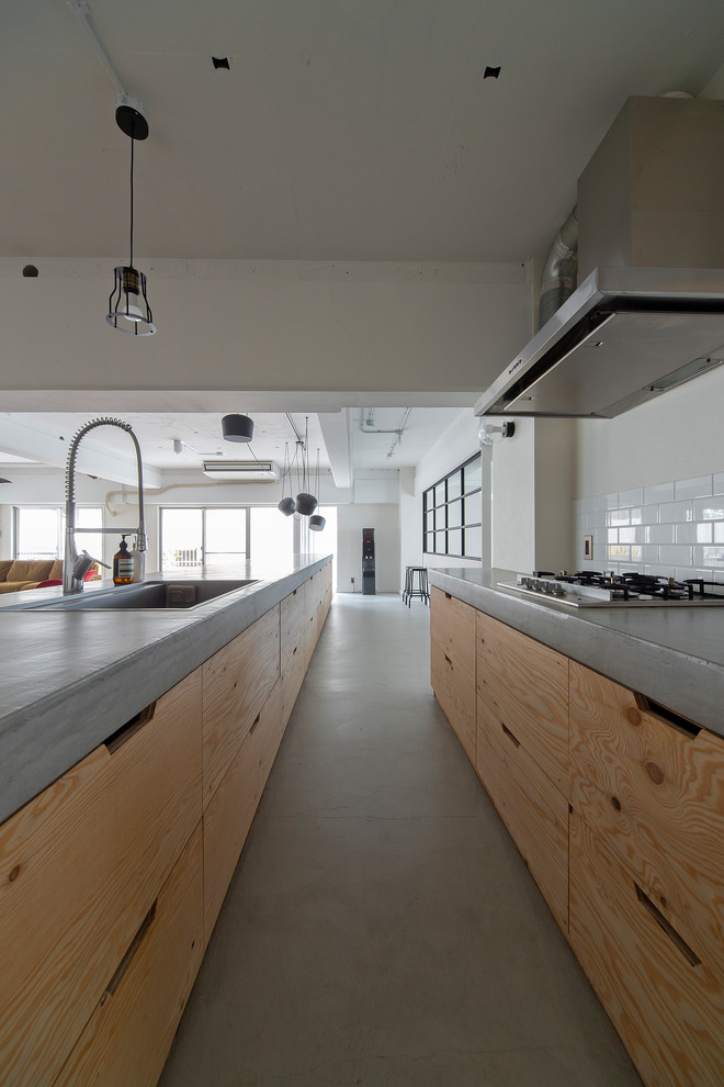 Design ideas for a large industrial galley open plan kitchen in Osaka with an undermount sink, beaded inset cabinets, medium wood cabinets, concrete benchtops, white splashback, subway tile splashback, stainless steel appliances, concrete floors, with island and grey floor.
