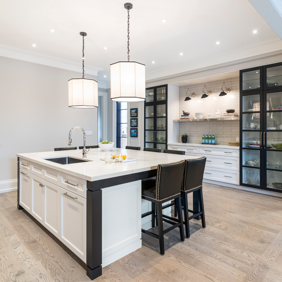 Open concept kitchen - transitional galley beige floor open concept kitchen idea in Toronto with an undermount sink, shaker cabinets, white cabinets, white backsplash, subway tile backsplash, stainless steel appliances and an island