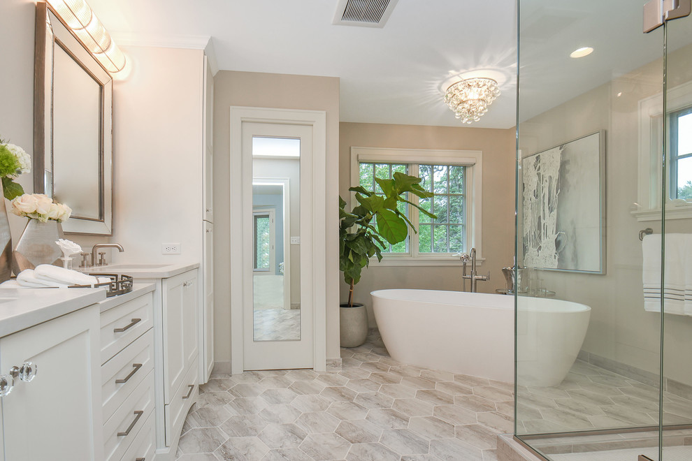 Design ideas for a large transitional master bathroom in Minneapolis with flat-panel cabinets, white cabinets, a freestanding tub, a corner shower, a two-piece toilet, white tile, glass sheet wall, brown walls, porcelain floors, an undermount sink, engineered quartz benchtops, multi-coloured floor, a hinged shower door and white benchtops.