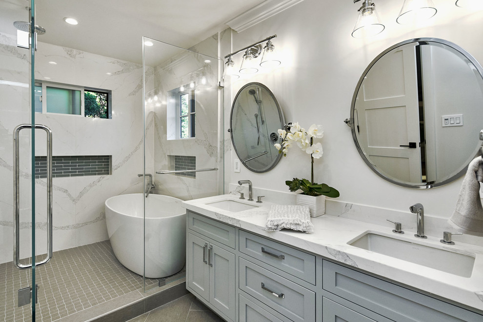 Design ideas for a mid-sized transitional master wet room bathroom in San Francisco with shaker cabinets, grey cabinets, white tile, stone slab, white walls, porcelain floors, an undermount sink, engineered quartz benchtops, grey floor, a hinged shower door, white benchtops and a freestanding tub.