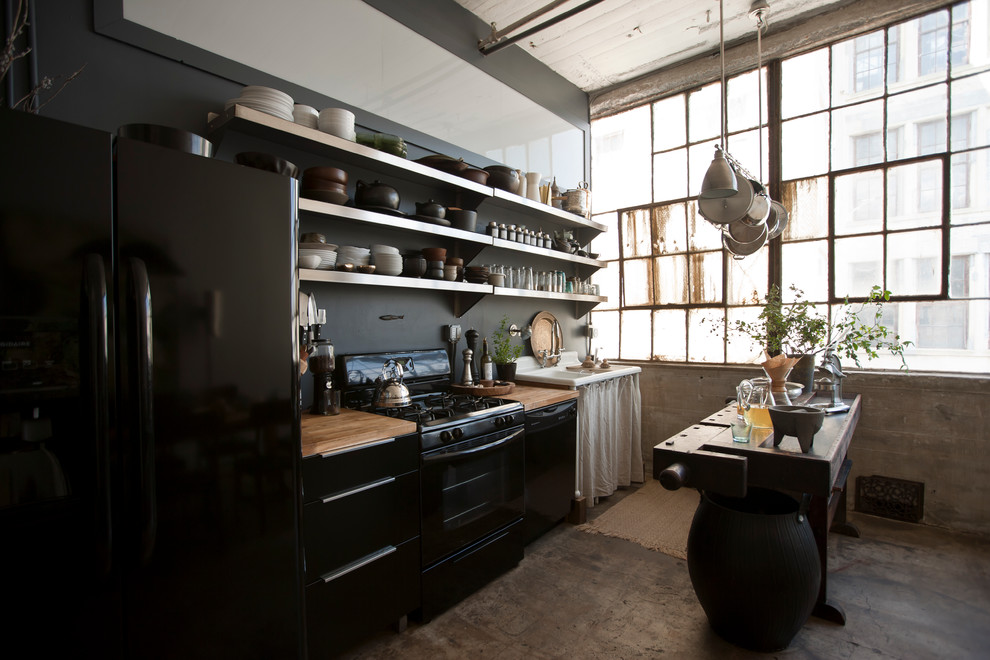 Inspiration for an industrial single-wall kitchen in New York with open cabinets, black appliances and wood benchtops.