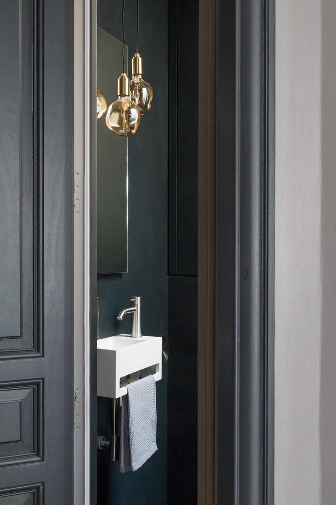 This is an example of a mid-sized contemporary powder room in Paris with a wall-mount toilet, black walls, a wall-mount sink and black floor.