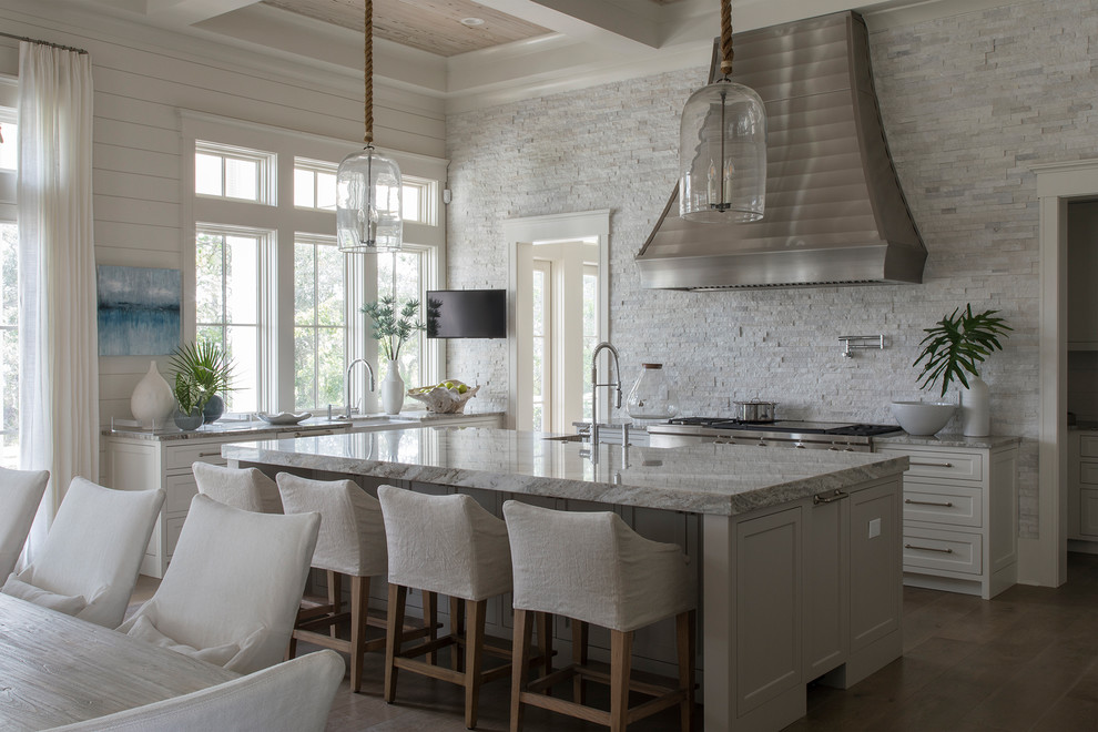 Design ideas for a beach style kitchen in Miami with a farmhouse sink, shaker cabinets, white cabinets, stainless steel appliances, dark hardwood floors, with island, brown floor and grey benchtop.