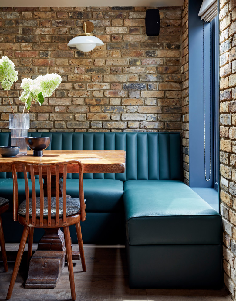 Inspiration for a contemporary kitchen/dining combo in London with light hardwood floors and brick walls.