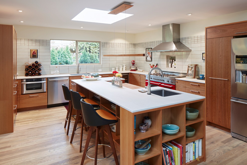 Inspiration for a modern l-shaped open plan kitchen in Portland with an undermount sink, flat-panel cabinets, medium wood cabinets, quartz benchtops, grey splashback, ceramic splashback, stainless steel appliances, light hardwood floors, with island and white benchtop.