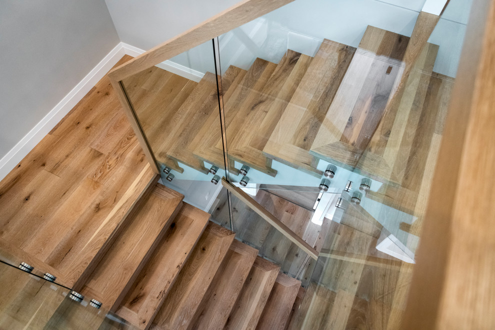 This is an example of a mid-sized contemporary wood u-shaped staircase in Other with wood risers and glass railing.