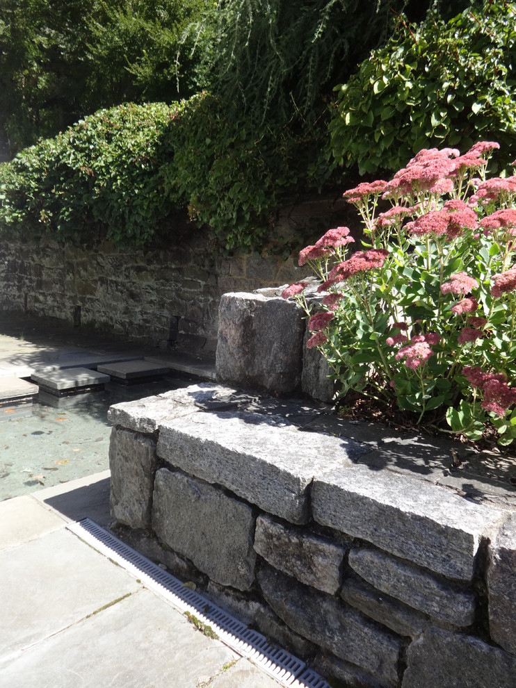 Photo of a small traditional backyard shaded garden in New York with a water feature and natural stone pavers.