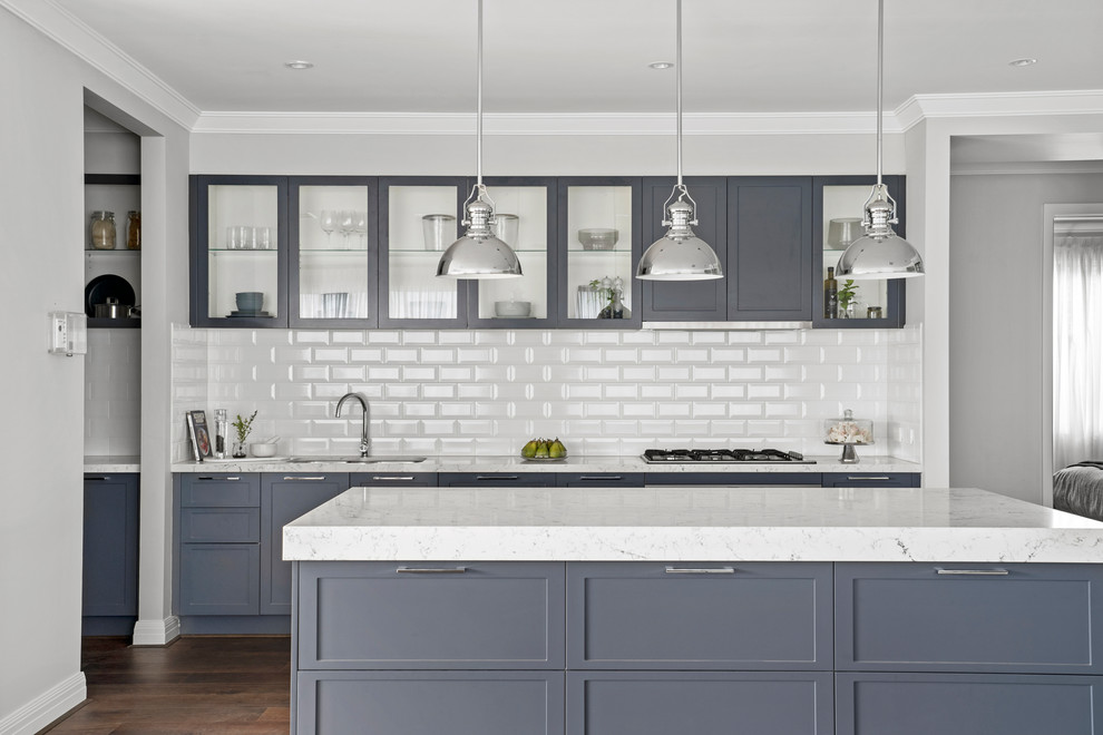 Design ideas for a transitional galley kitchen in Melbourne with an undermount sink, shaker cabinets, grey cabinets, white splashback, subway tile splashback, medium hardwood floors, with island, brown floor and white benchtop.