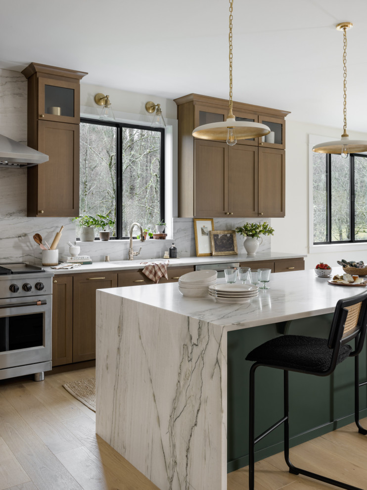 Inspiration for a large transitional l-shaped light wood floor and beige floor open concept kitchen remodel in Seattle with a farmhouse sink, shaker cabinets, green cabinets, quartzite countertops, gray backsplash, stone slab backsplash, stainless steel appliances, an island and gray countertops