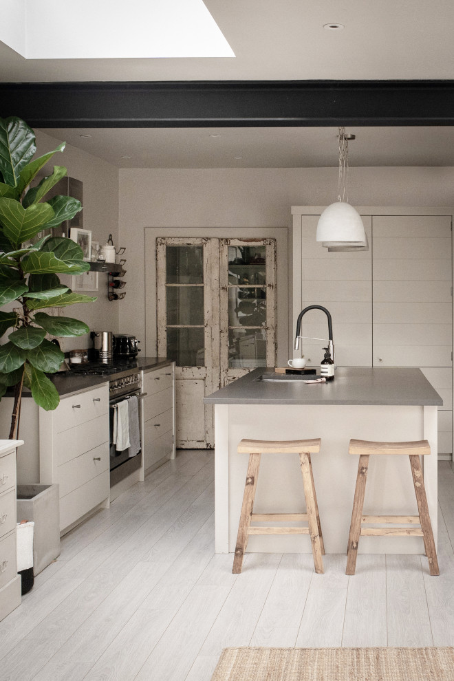 Design ideas for a medium sized scandinavian u-shaped kitchen in London with a submerged sink, flat-panel cabinets, white cabinets, engineered stone countertops, stainless steel appliances, light hardwood flooring, an island, grey worktops and exposed beams.