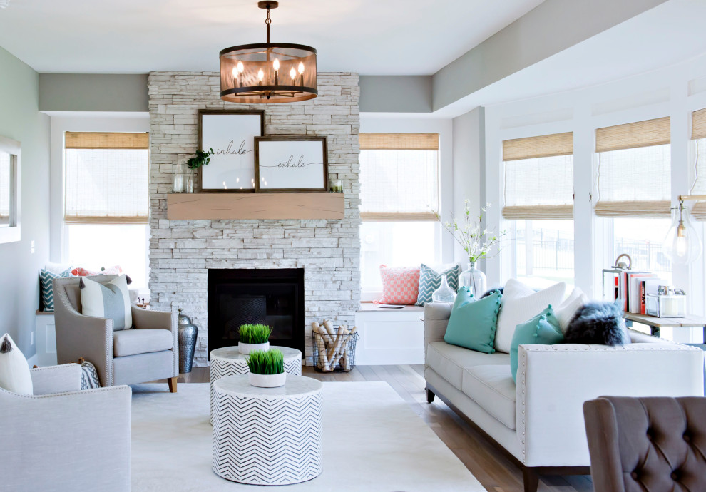 This is an example of a mid-sized beach style open concept living room in Kansas City with grey walls, light hardwood floors, a standard fireplace, a stone fireplace surround and multi-coloured floor.