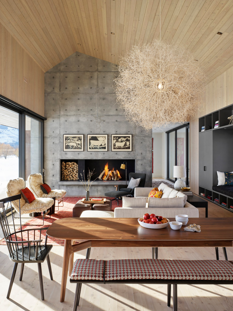 Diseño de salón abierto y abovedado minimalista sin televisor con paredes beige, suelo de madera clara, chimenea lineal, marco de chimenea de hormigón, suelo beige y madera