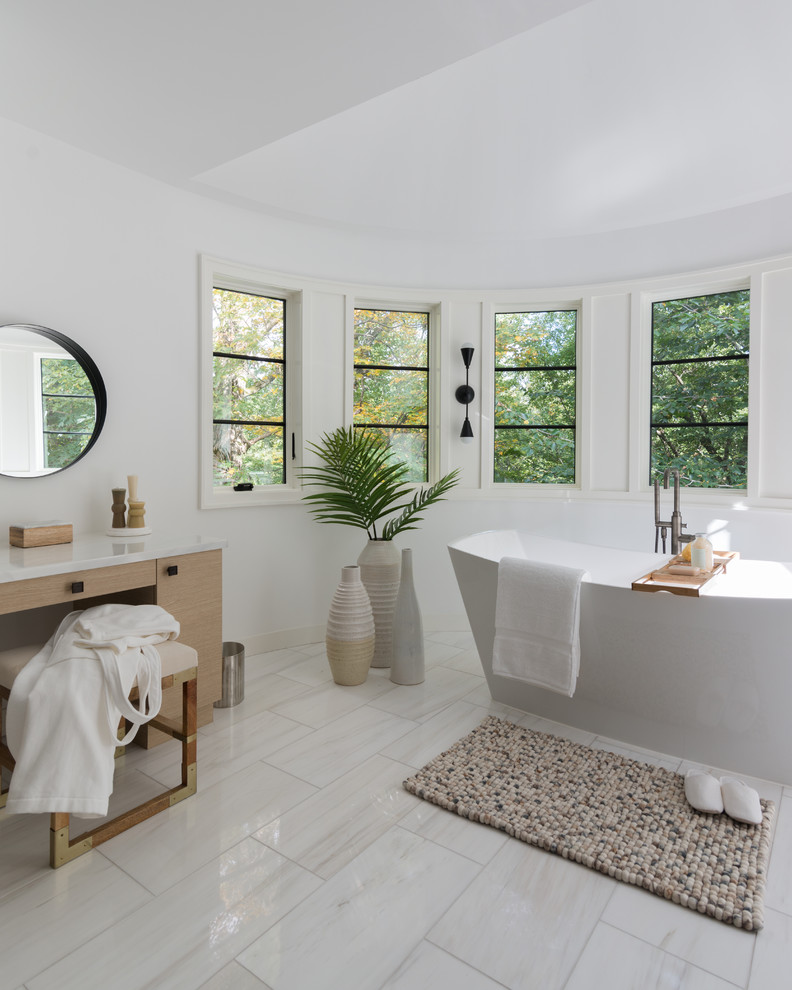 Design ideas for a large contemporary master bathroom in New York with flat-panel cabinets, light wood cabinets, a freestanding tub, a corner shower, white walls, white floor, a hinged shower door, white benchtops, limestone floors, limestone benchtops and an undermount sink.