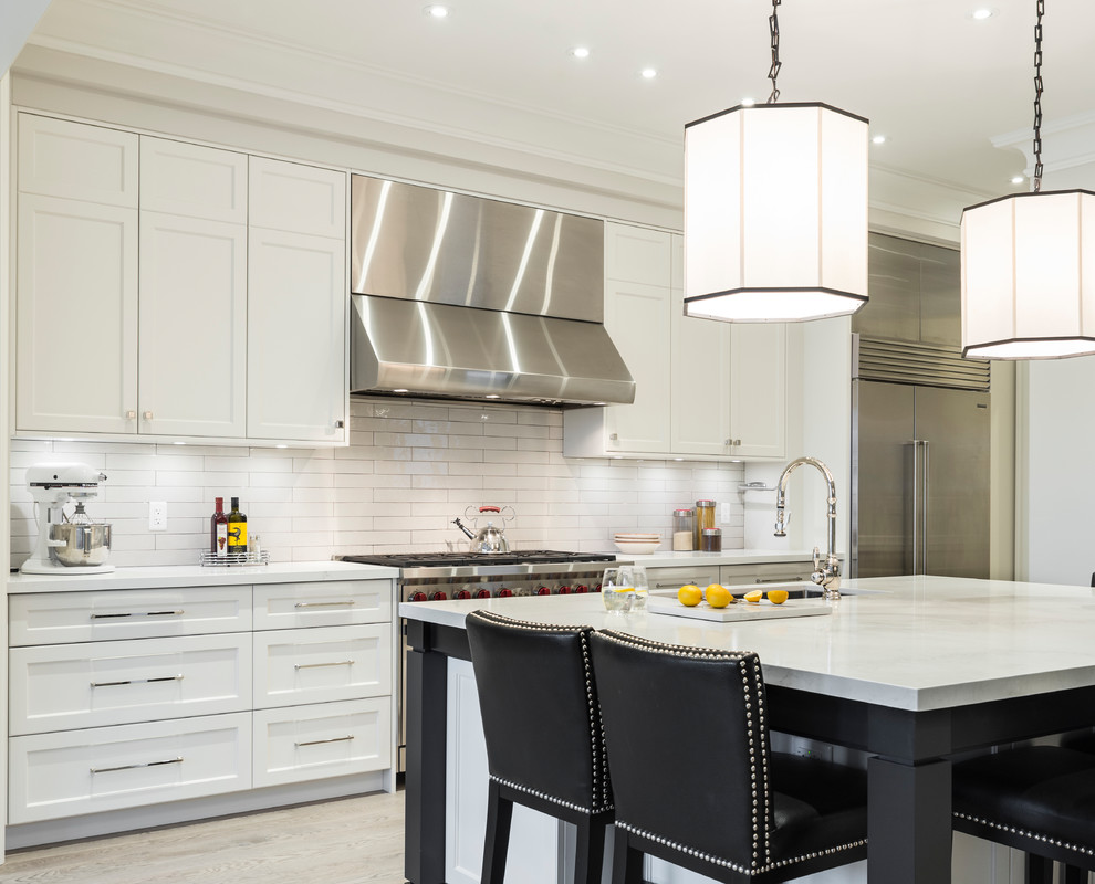 Example of a transitional galley beige floor open concept kitchen design in Toronto with an undermount sink, shaker cabinets, white cabinets, white backsplash, subway tile backsplash, stainless steel appliances and an island