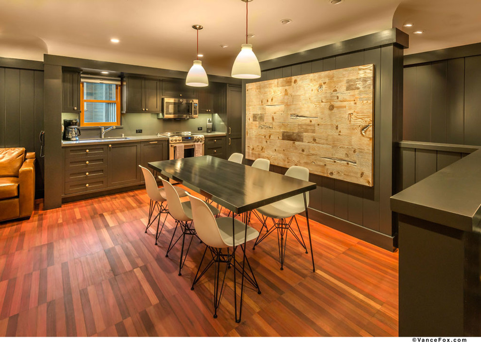 This is an example of a small transitional single-wall eat-in kitchen in Sacramento with a single-bowl sink, recessed-panel cabinets, black cabinets, solid surface benchtops, stainless steel appliances, medium hardwood floors and no island.