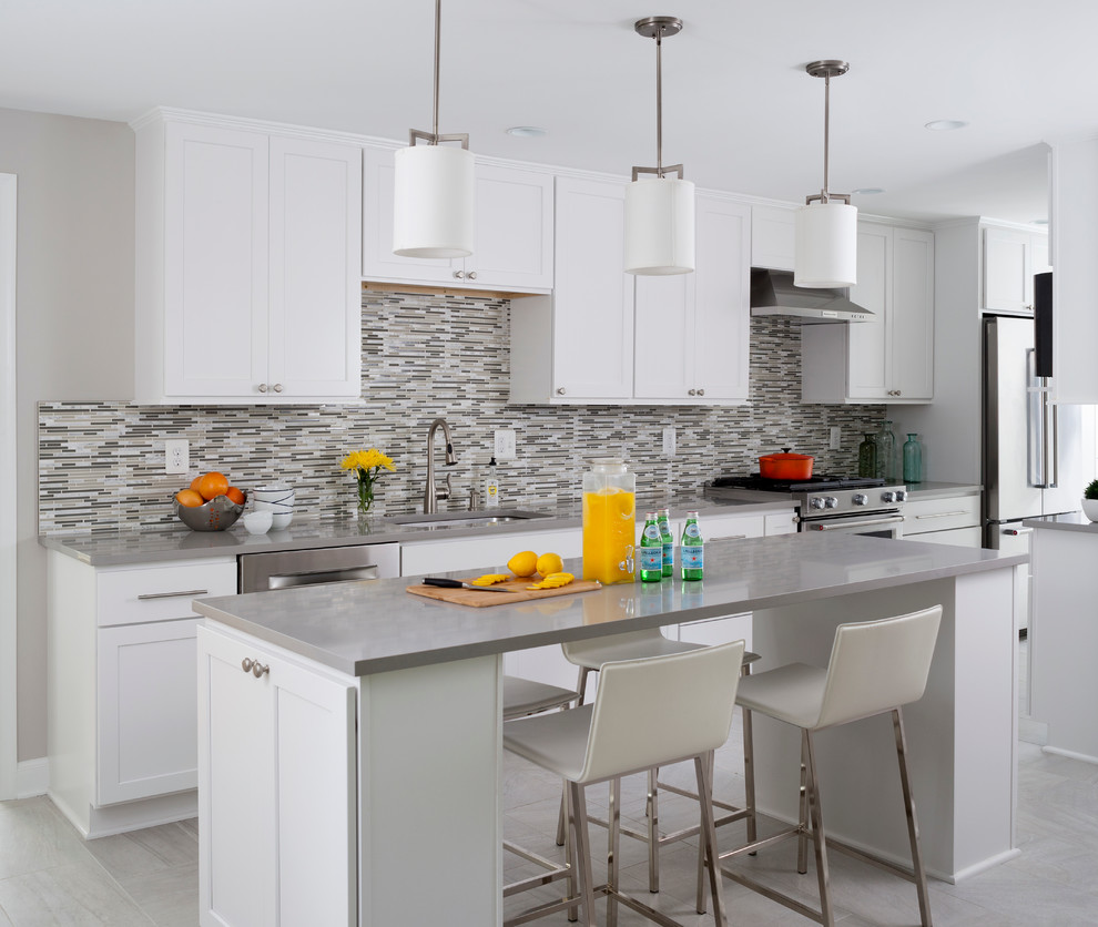 Photo of a large transitional kitchen in DC Metro with white cabinets, beige splashback, glass tile splashback, stainless steel appliances and with island.