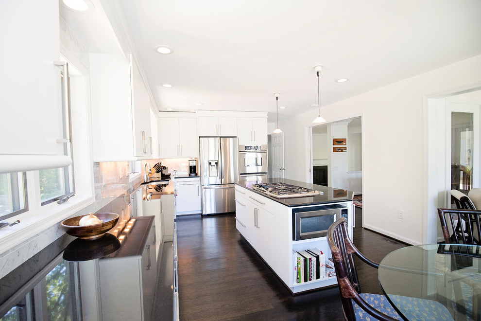 Large transitional l-shaped eat-in kitchen in Baltimore with an undermount sink, flat-panel cabinets, white cabinets, granite benchtops, grey splashback, marble splashback, stainless steel appliances, dark hardwood floors, with island and black floor.