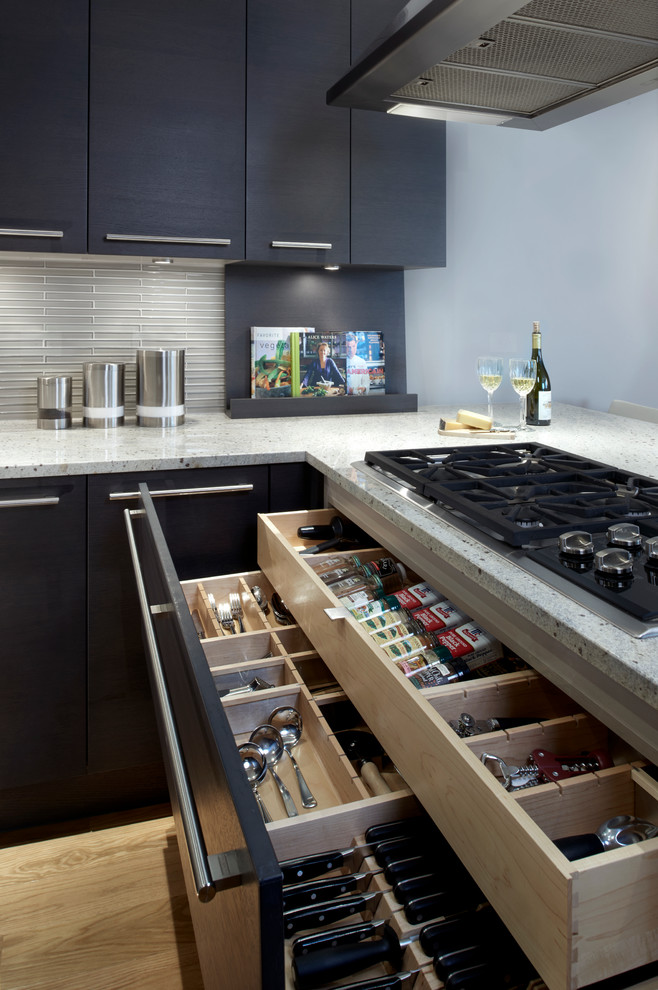 Design ideas for a large contemporary galley eat-in kitchen in Chicago with an undermount sink, flat-panel cabinets, black cabinets, granite benchtops, grey splashback, glass tile splashback, stainless steel appliances, light hardwood floors and no island.