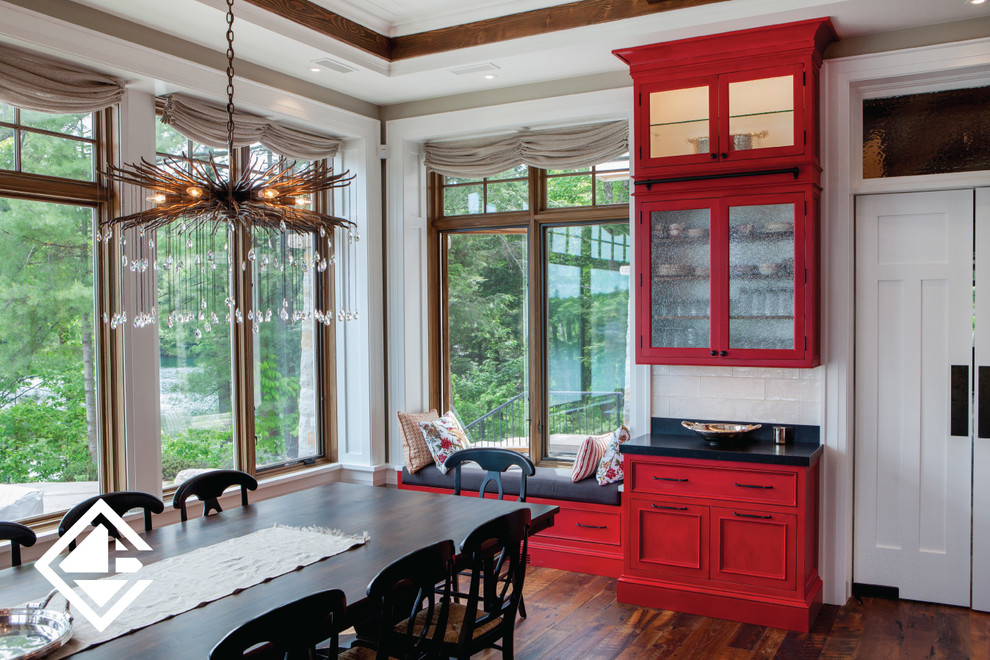 Eat-in kitchen - huge rustic l-shaped medium tone wood floor eat-in kitchen idea with a farmhouse sink, raised-panel cabinets, red cabinets, granite countertops, white backsplash, stainless steel appliances and an island
