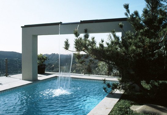Photo of a large modern backyard rectangular lap pool in Los Angeles with a water feature and concrete slab.