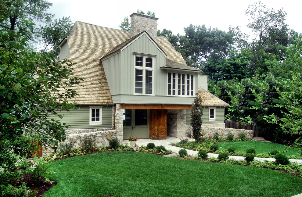 Large traditional two-storey green house exterior in Chicago with a gambrel roof, a shingle roof and vinyl siding.