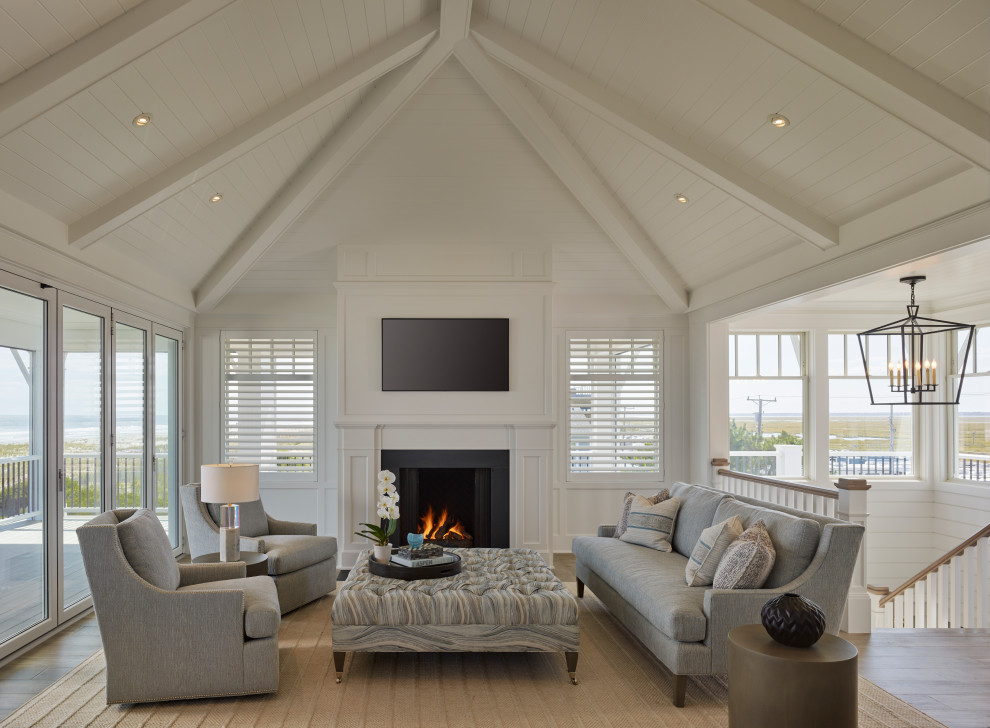 Large beach style open concept living room in Other with white walls, medium hardwood floors, a standard fireplace, a metal fireplace surround, a built-in media wall and vaulted.