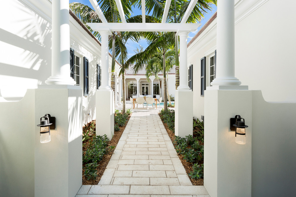 Inspiration for a large tropical side yard patio in Miami with natural stone pavers.