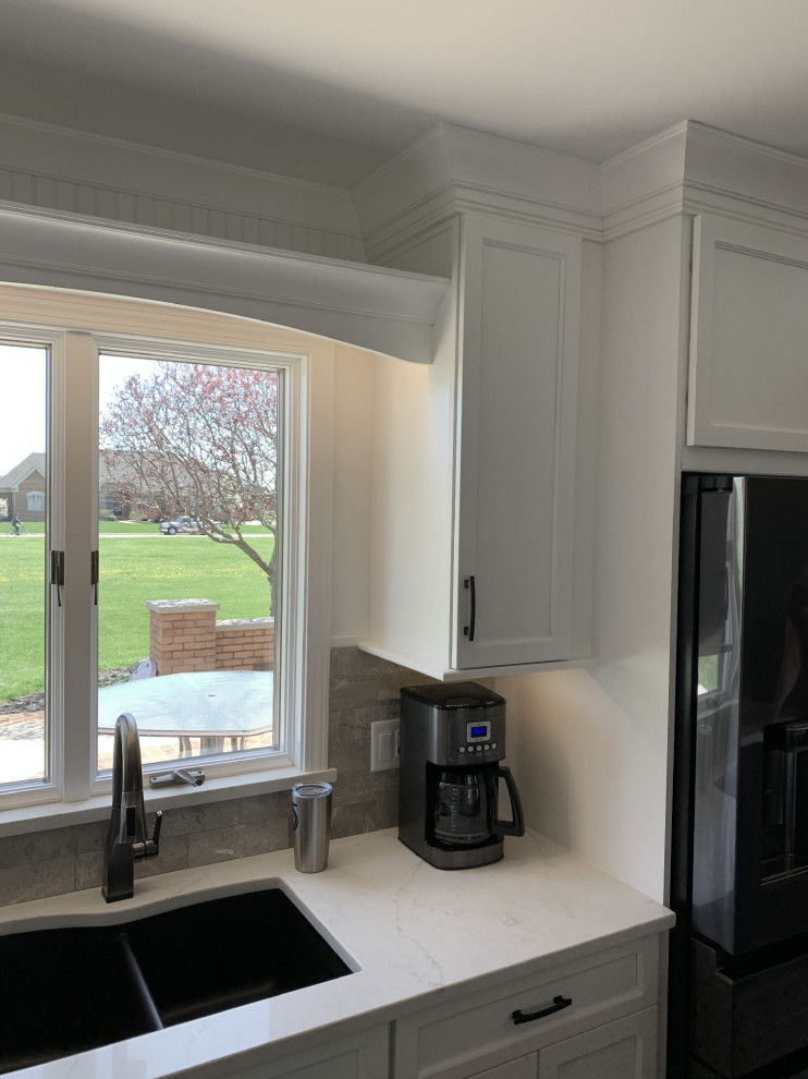 Inspiration for a large transitional l-shaped vinyl floor and gray floor eat-in kitchen remodel with an undermount sink, recessed-panel cabinets, white cabinets, quartz countertops, gray backsplash, ceramic backsplash, stainless steel appliances, an island and white countertops