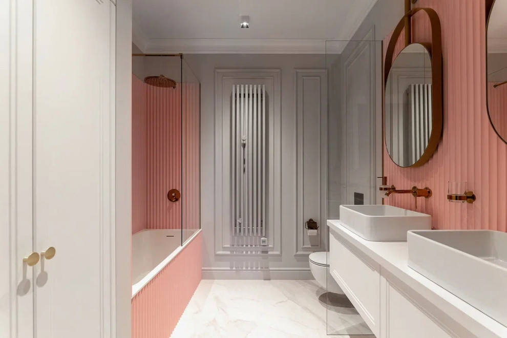 Свежая идея для дизайна: большая детская, серо-белая ванная комната в современном стиле с фасадами с выступающей филенкой, белыми фасадами, ванной в нише, инсталляцией, розовой плиткой, серыми стенами, полом из керамогранита, накладной раковиной, столешницей из искусственного камня, серым полом, душем с распашными дверями, белой столешницей, зеркалом с подсветкой, тумбой под две раковины, подвесной тумбой, многоуровневым потолком и панелями на части стены - отличное фото интерьера