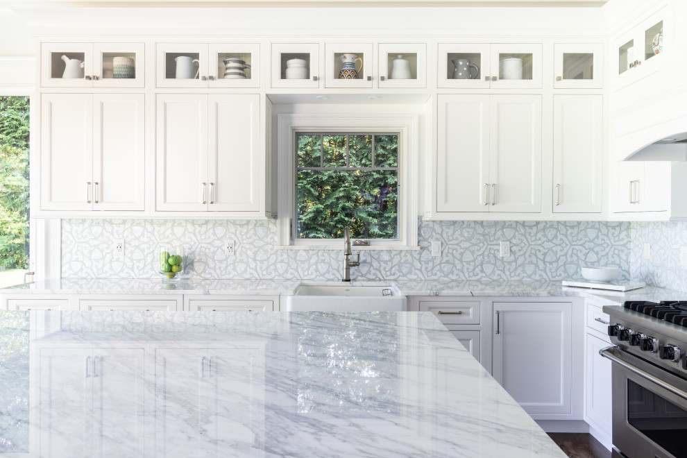 Mid-sized traditional l-shaped eat-in kitchen in Charlotte with a farmhouse sink, recessed-panel cabinets, white cabinets, marble benchtops, blue splashback, mosaic tile splashback, stainless steel appliances, dark hardwood floors, with island, brown floor, multi-coloured benchtop and recessed.