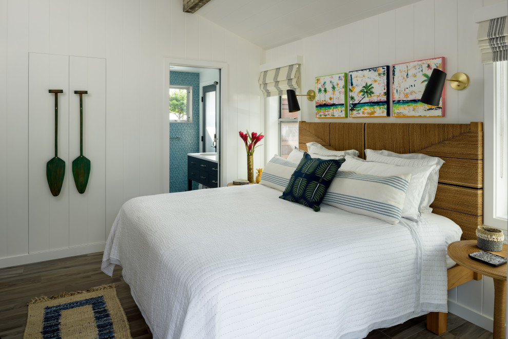 Photo of a mid-sized beach style guest bedroom in Hawaii with white walls, porcelain floors, grey floor, exposed beam and panelled walls.